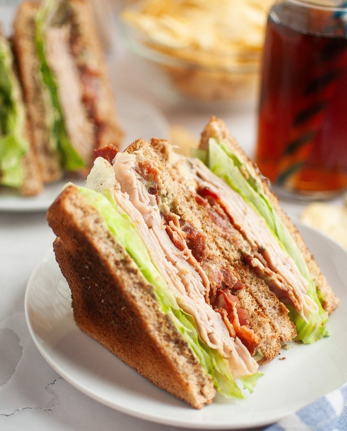 A turkey blt sandwich sliced in half on a white plate. 