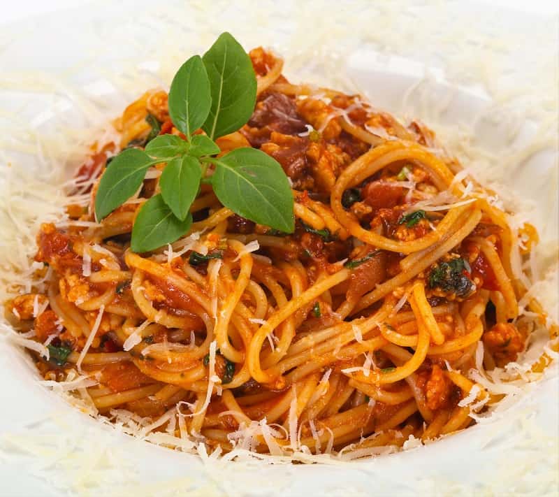 Healthy spaghetti bolognese topped with fresh grated parmesan in a bowl.