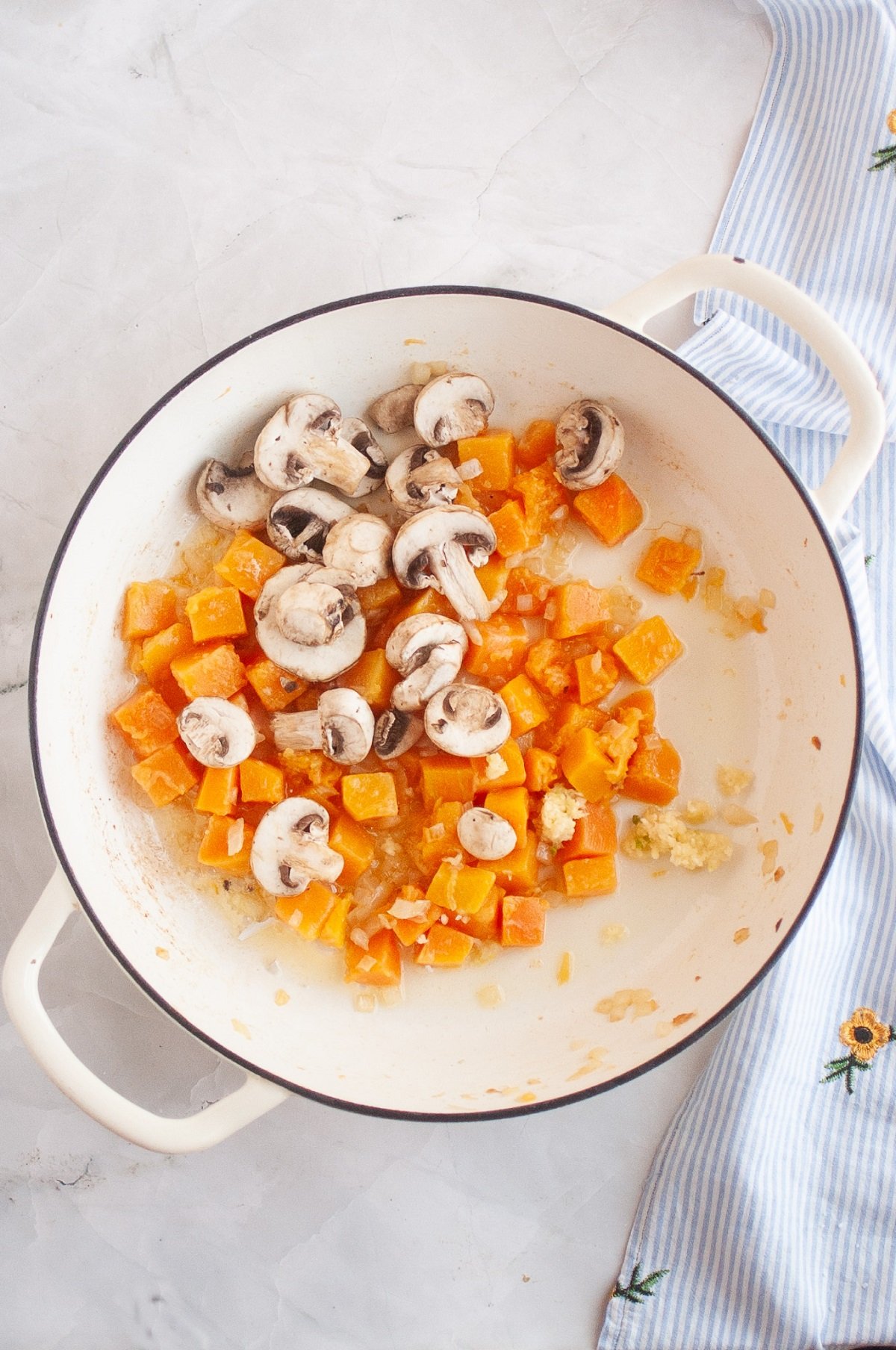 Squash and mushrooms are sauteed in a pan. 