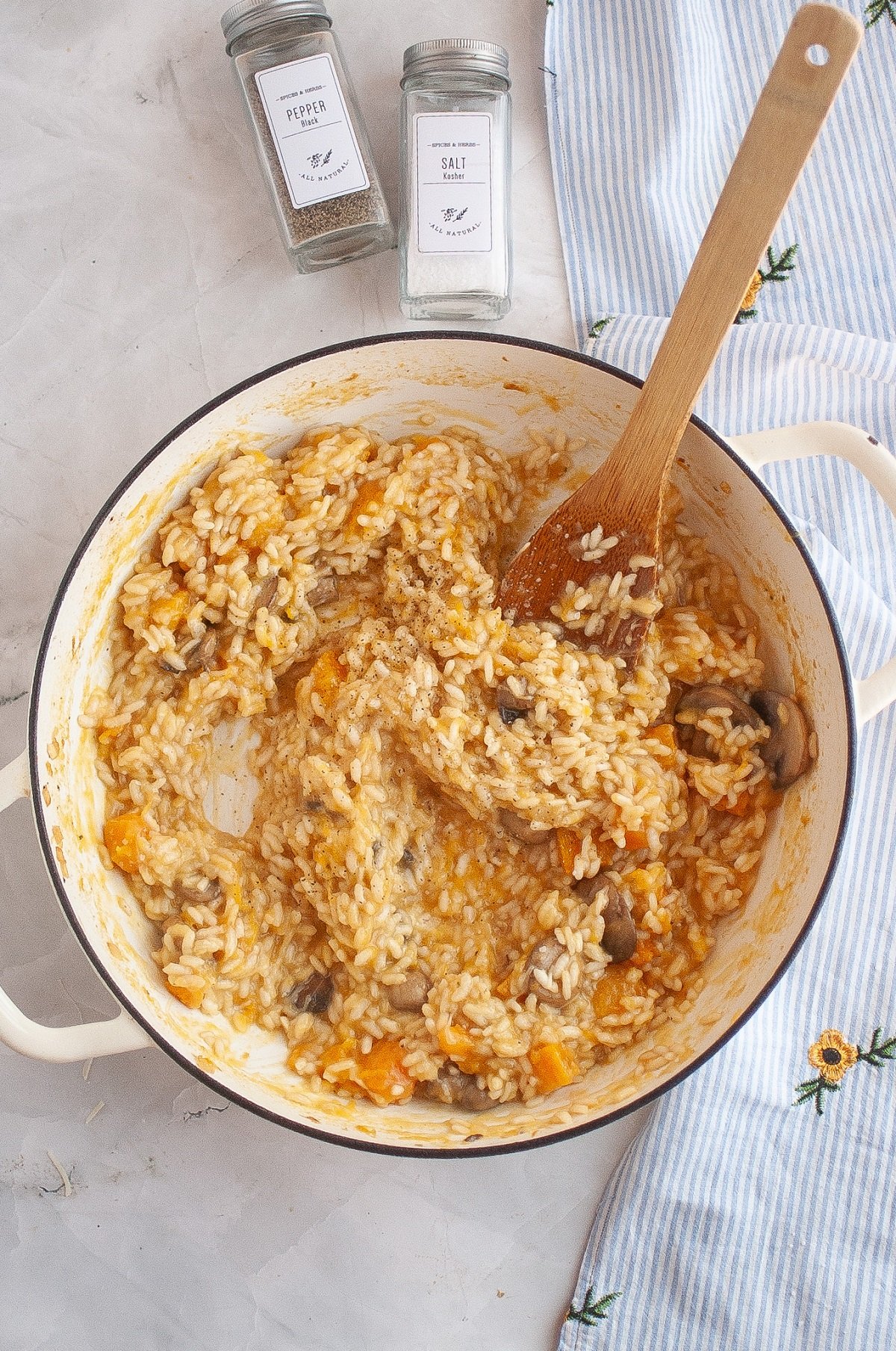 A wooden spoon stirs the butternut squash risotto as it cooks. 