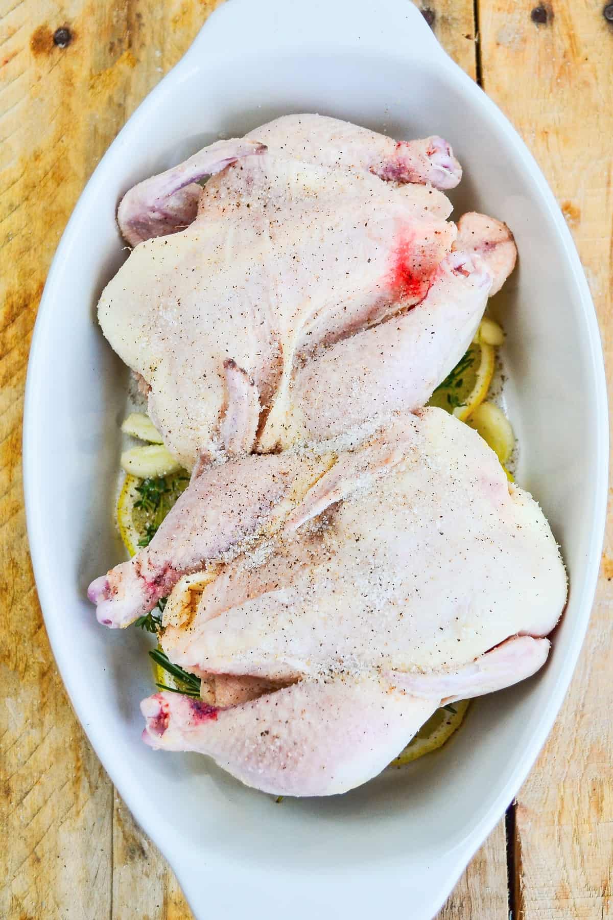Game hens on a bed of lemons in a baking dish. 