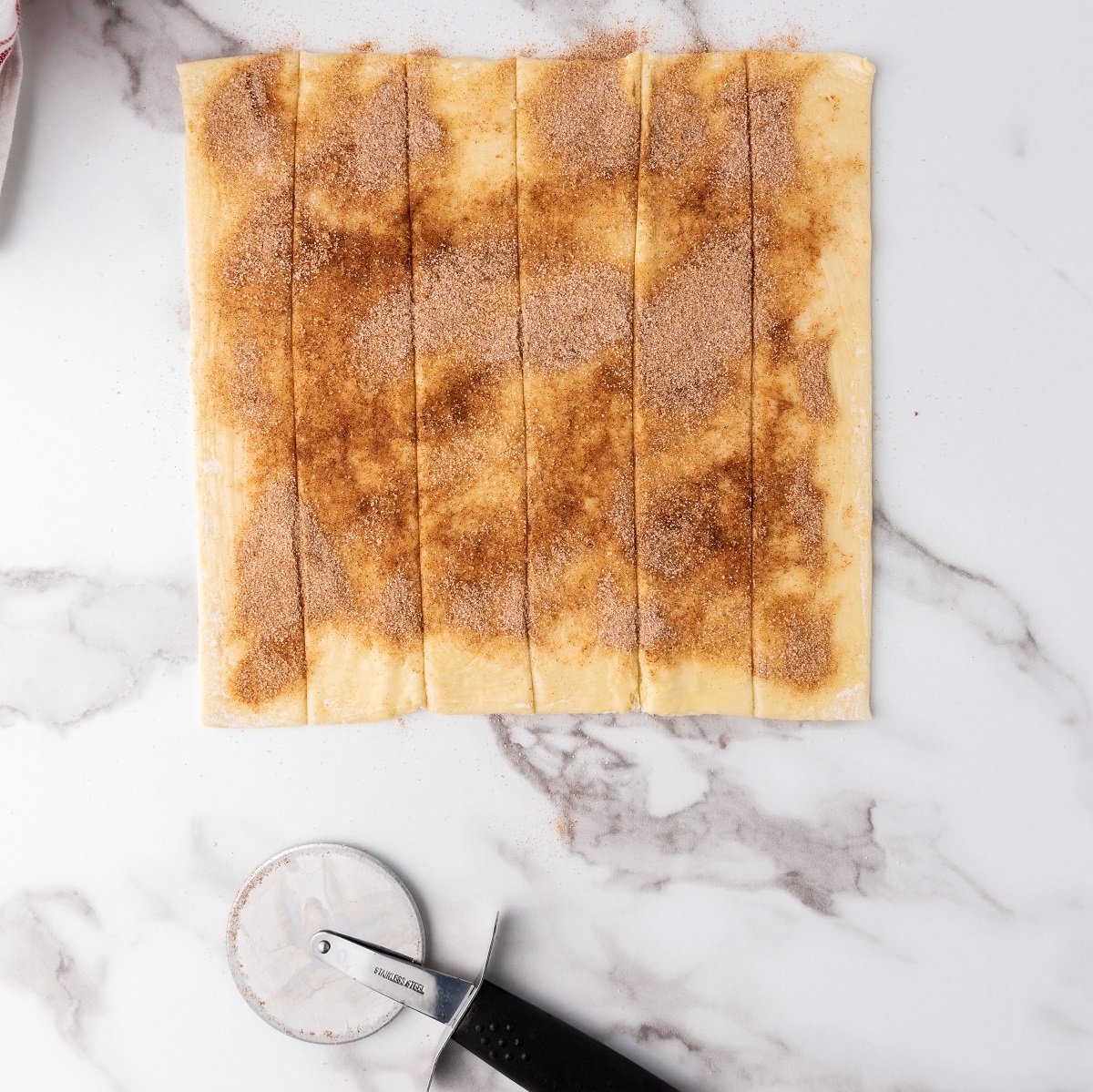 Puff pastry sheets are brushed with melted butter and cinnamon sugar. 