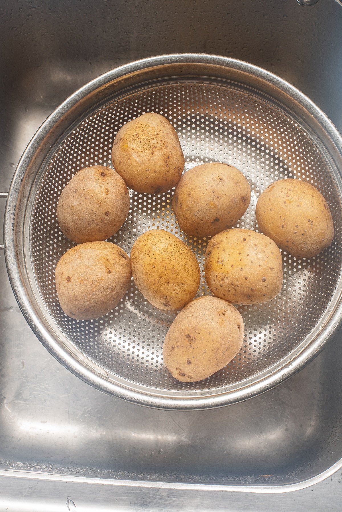 Boiled potatoes are drained in a colander. 