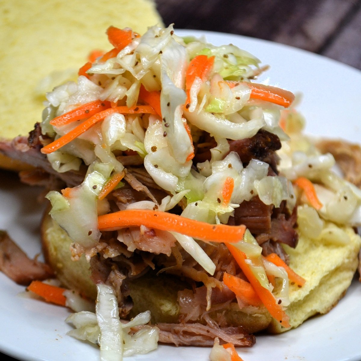 Vingear coleslaw recipe piled over pulled pork on a plate.