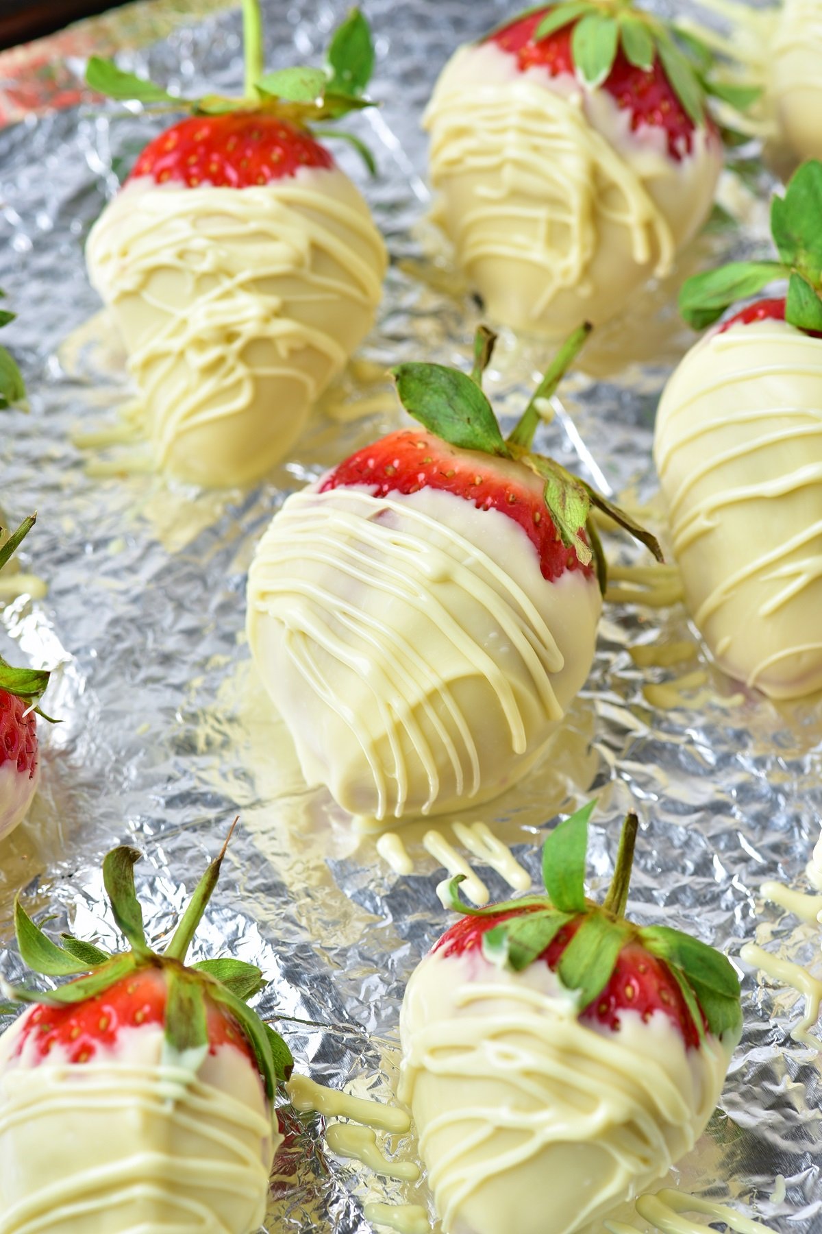 White chocolate is drizzled over chocolate covered strawberries to add a decorative touch. 