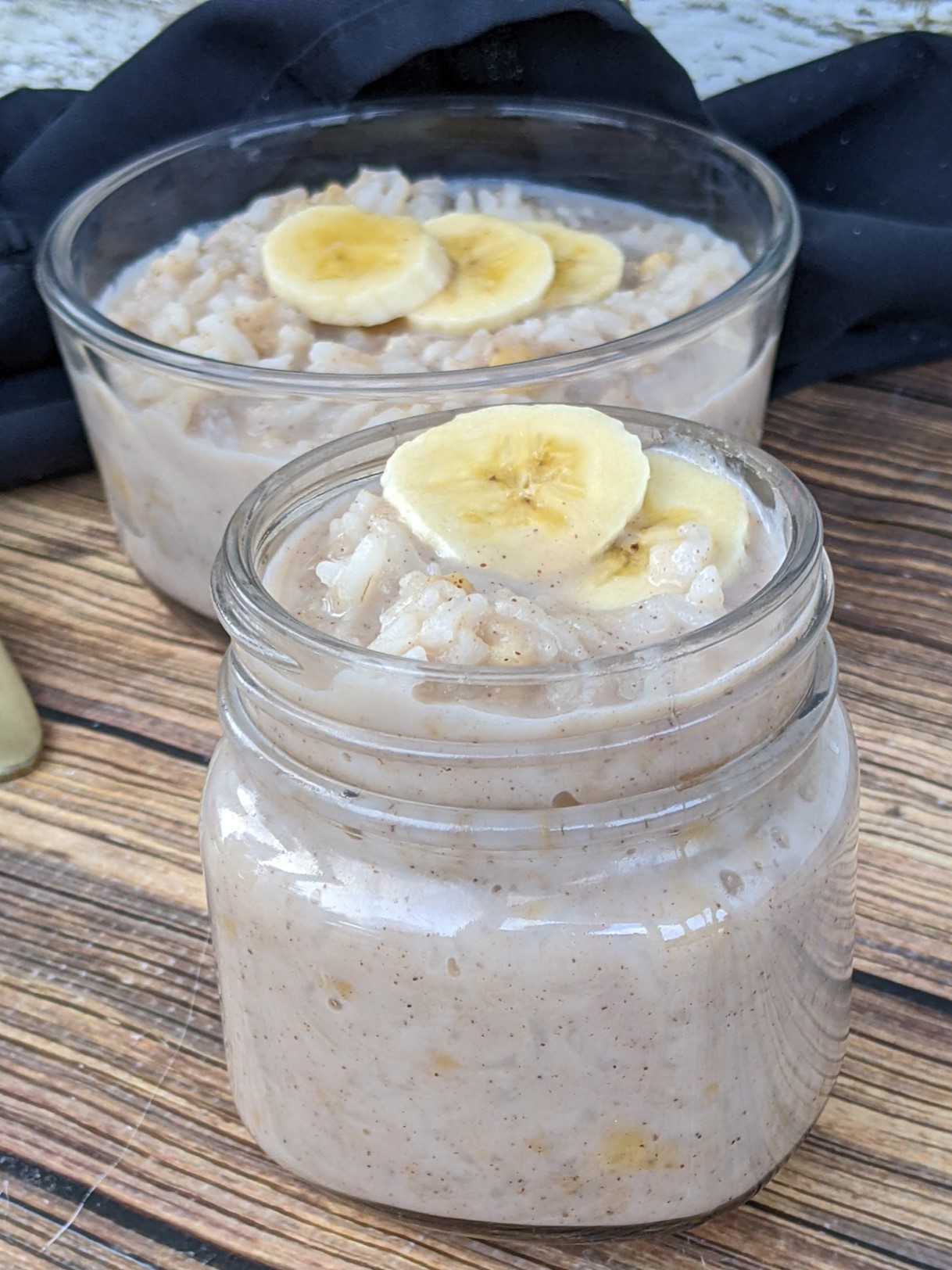 A small jar with rice pudding topped with slices of bananas. 