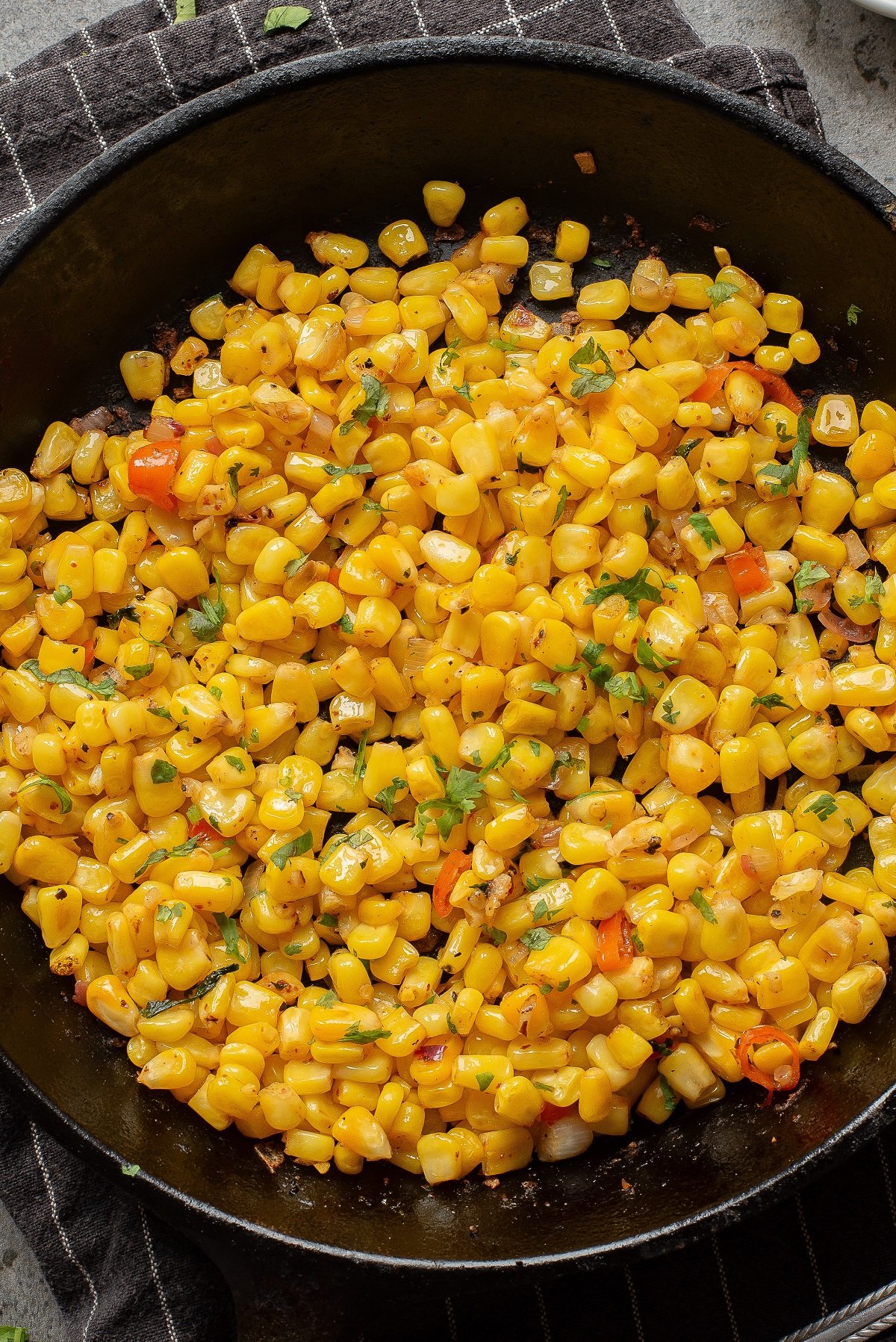 Skillet roasted corn garnished with cilantro in a cast iron skillet.