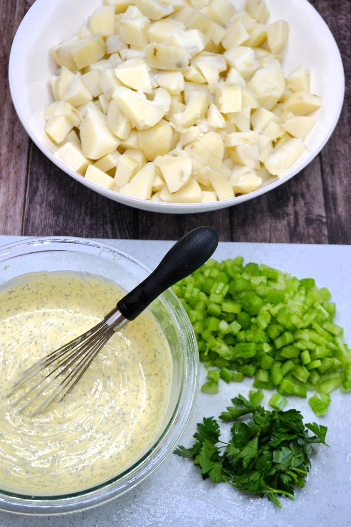 Chopped potatoes in a bowl and the dressing for potato salad.