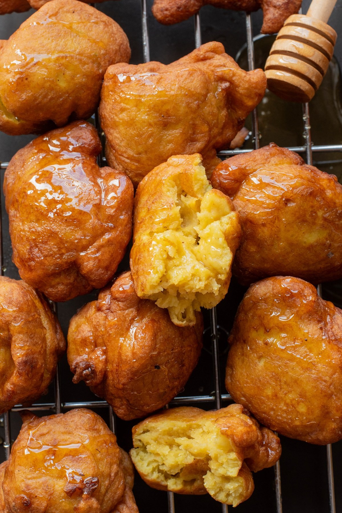 A crispy pumpkin fritter on a tray is torn in half to show the soft center. 