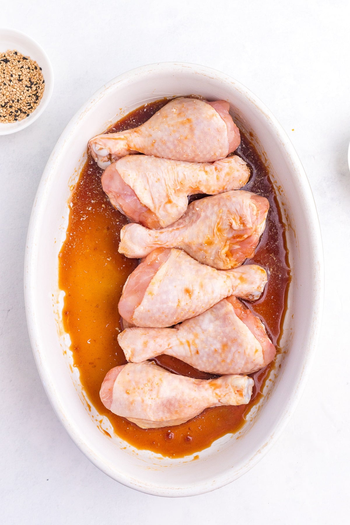 Chicken legs are arranged on a platter and topped with teriyaki sauce. 