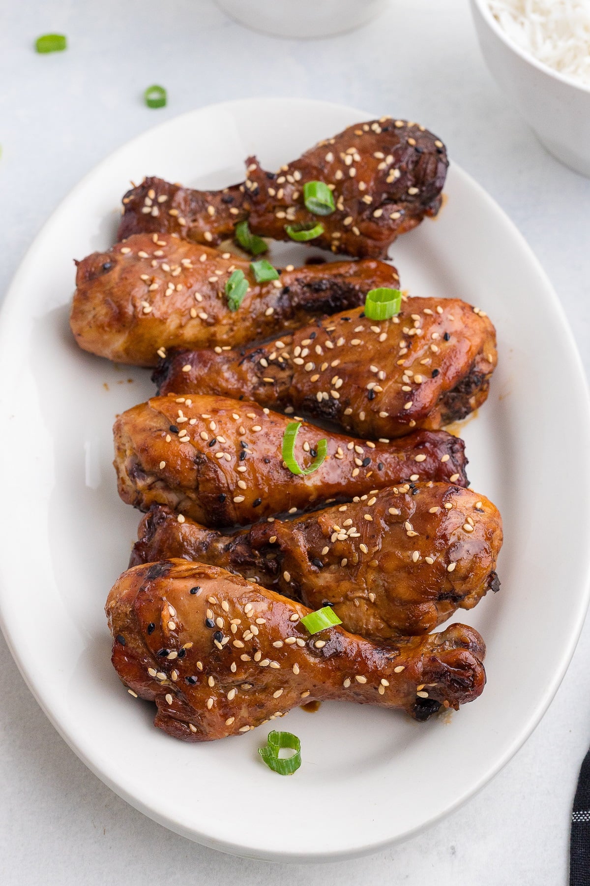 Chicken drumsticks garnished with sesame seeds and green onions. 