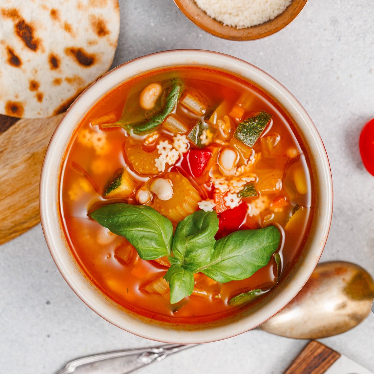 Top view of a bowl of veggie soup garnished with basil. 