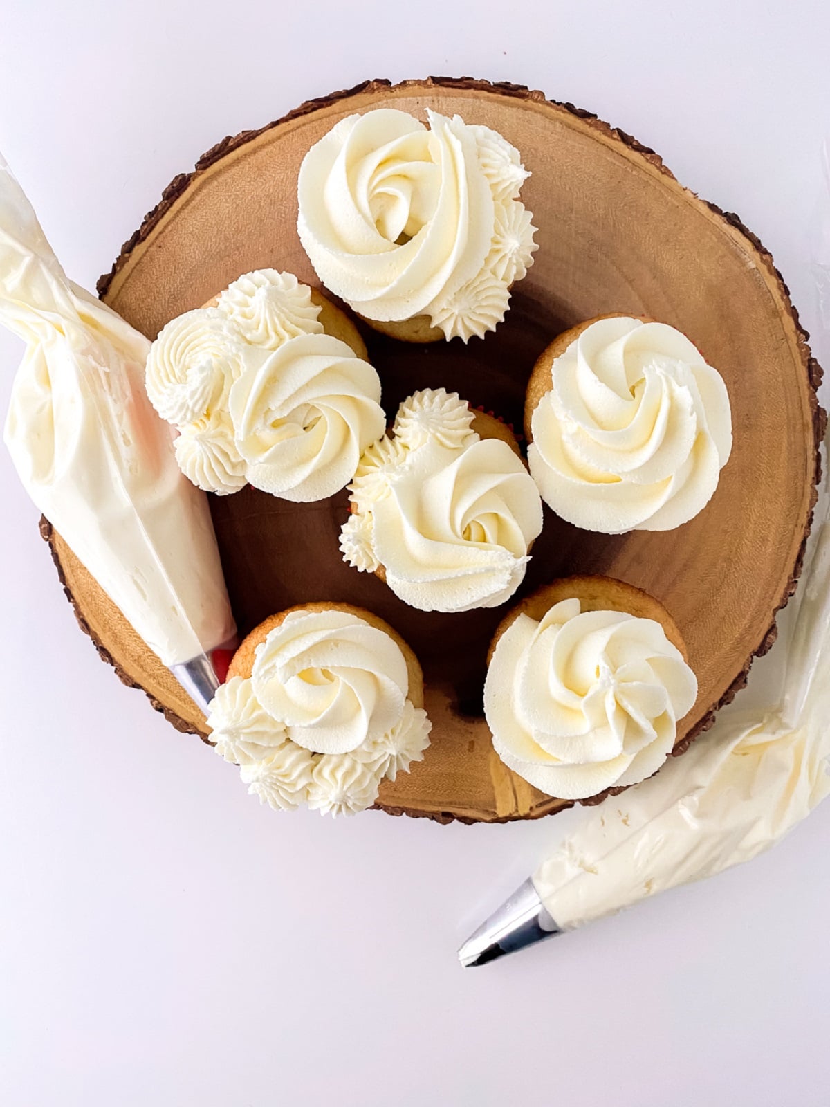 Piping bags filled with fluffy vanilla frost cupcakes.