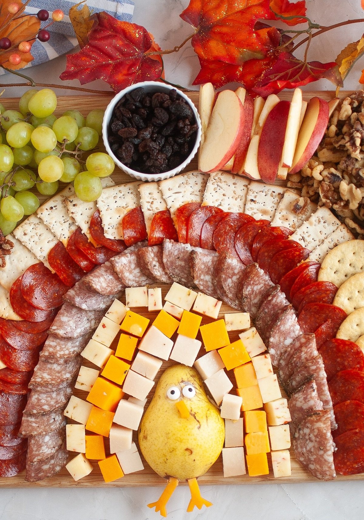 A charcuterie board made to look like a Thanksgiving turkey on a wooden board.