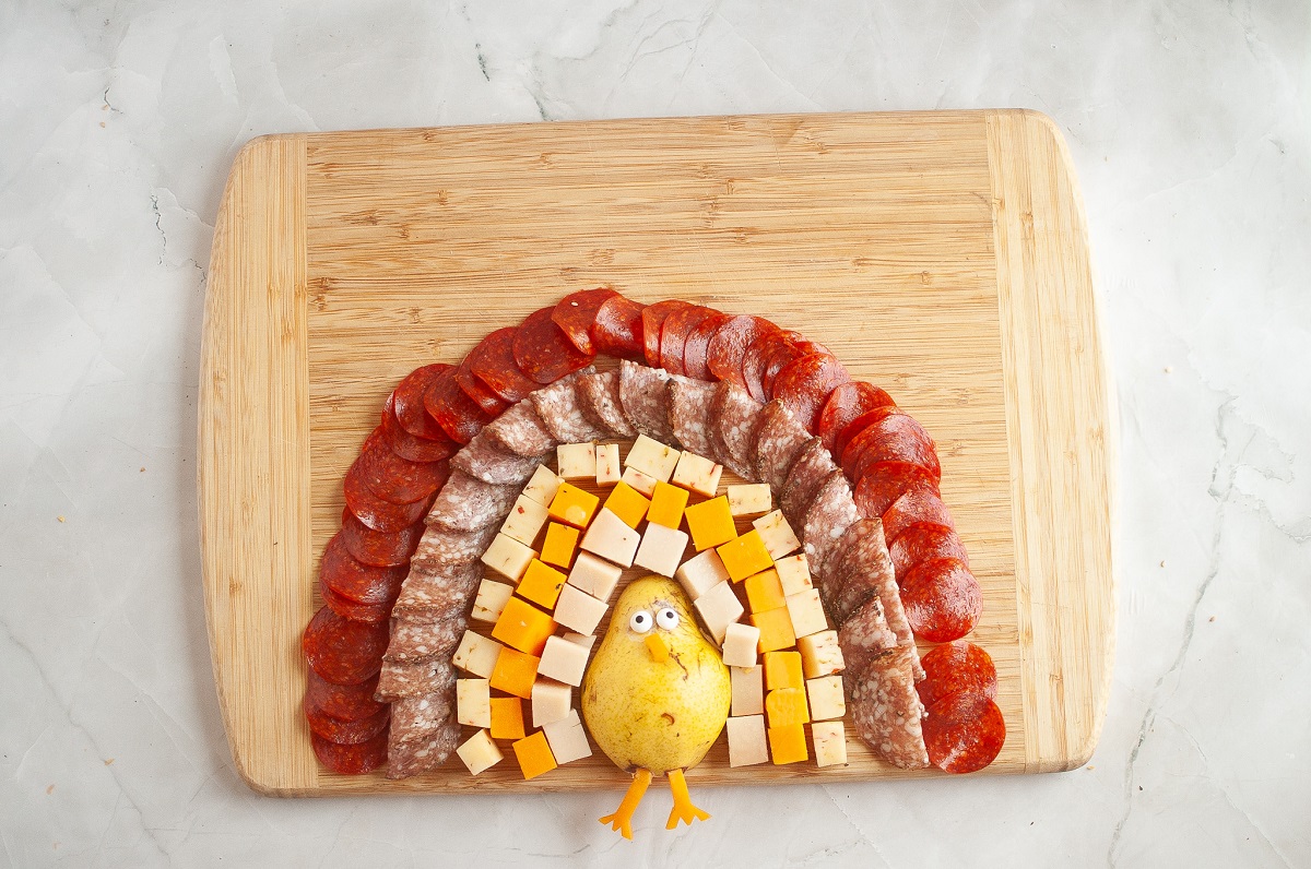 The meat and cheese surrounds the pear to form the feathers of the turkey.