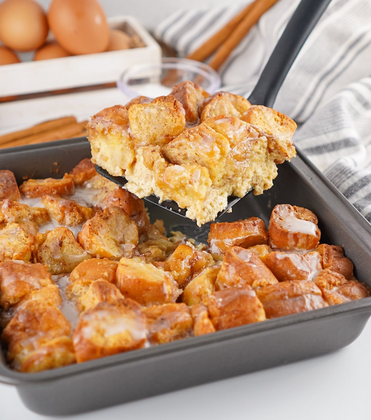A slice of bread pudding made with donuts is served with a spatula. 
