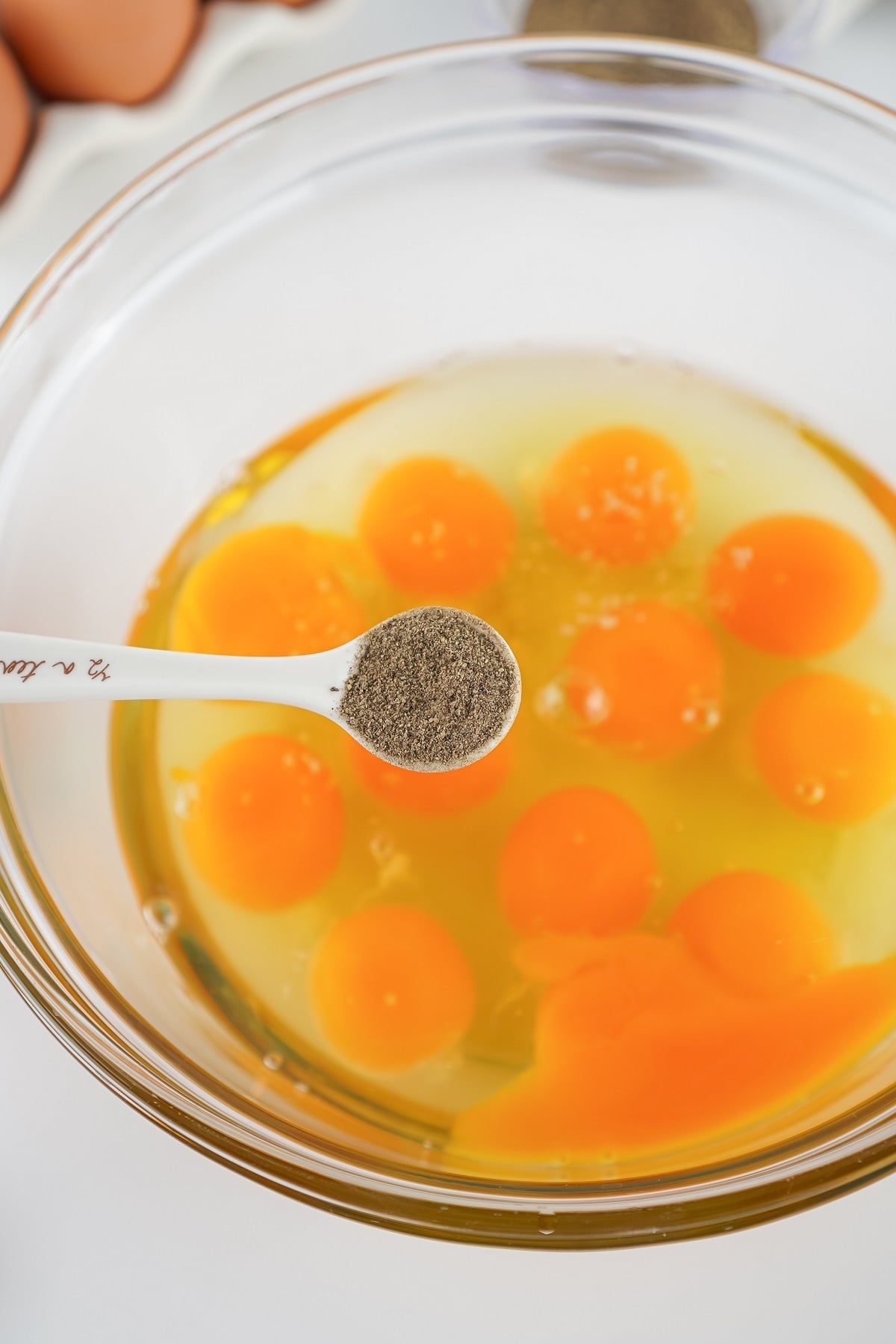 Fresh eggs are scrambled in a bowl with salt, pepper and milk. 