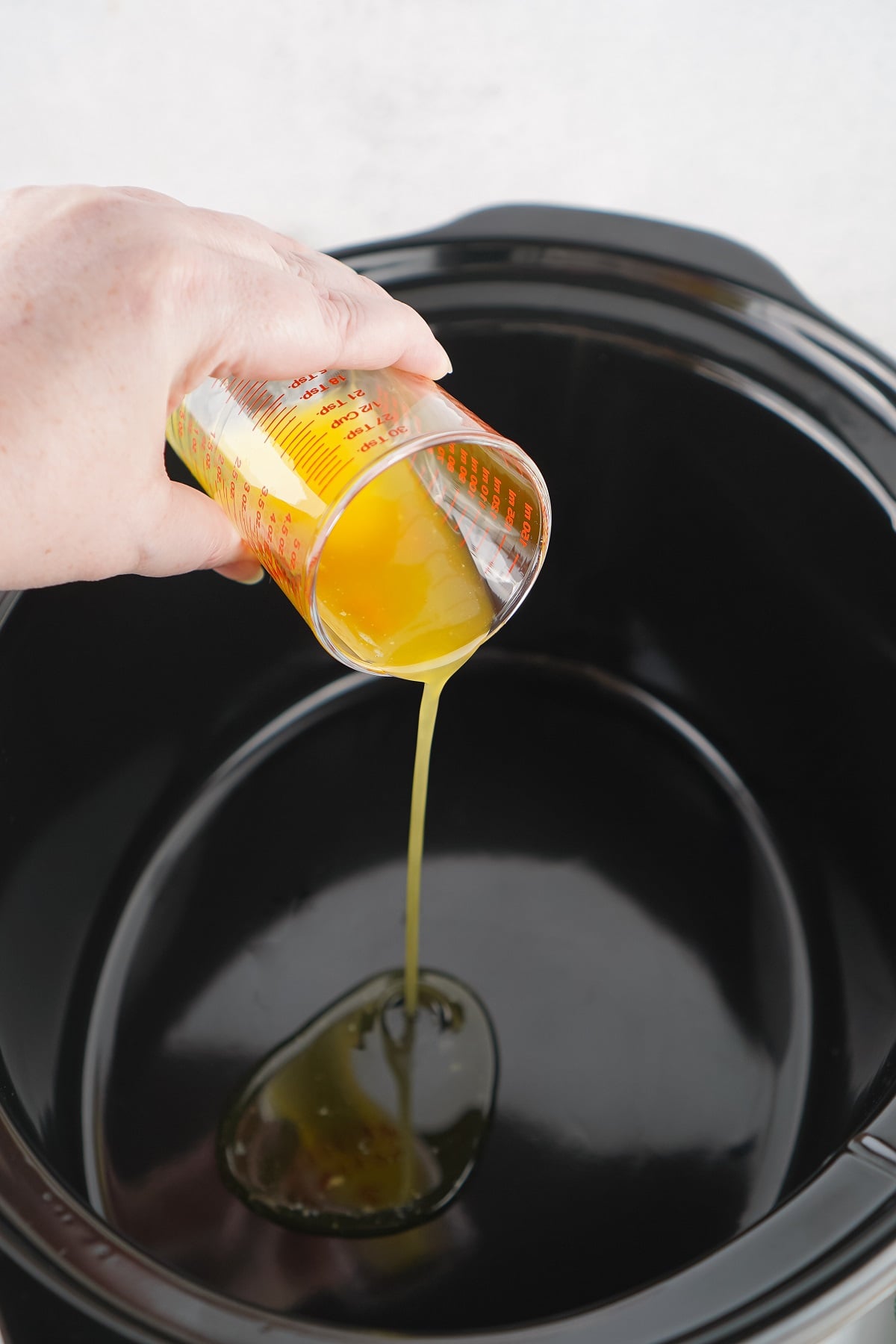 Melted butter is poured into a slow cooker. 