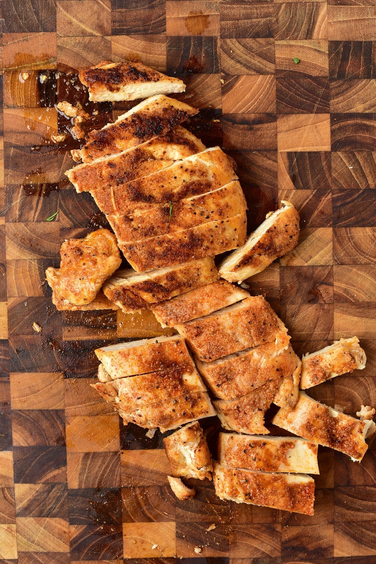 Grilled chicken is sliced on a cutting board.