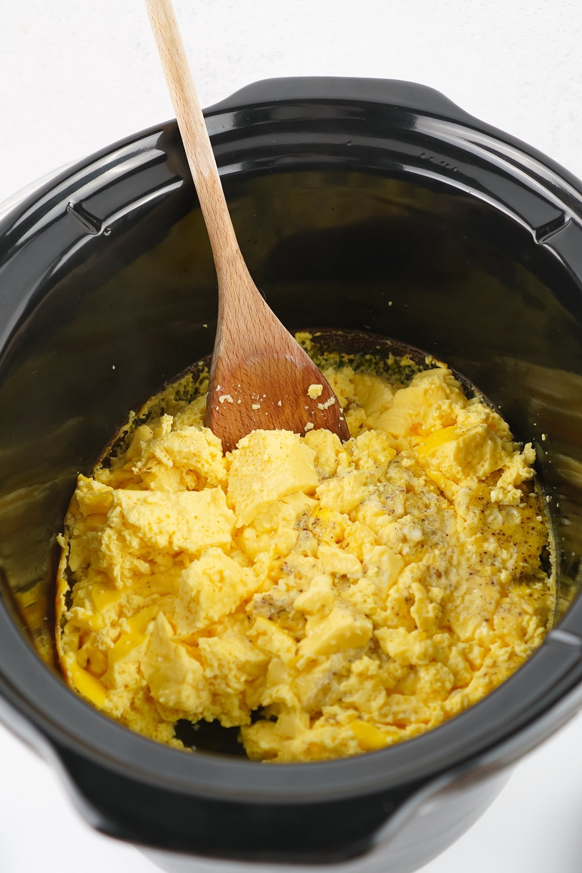 Cooked eggs are scrambled in the slow cooker. 