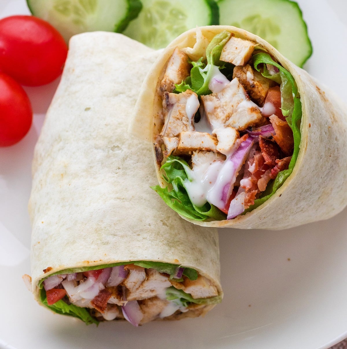 Grilled chicken wrap sliced in half and ready to serve on a plate.