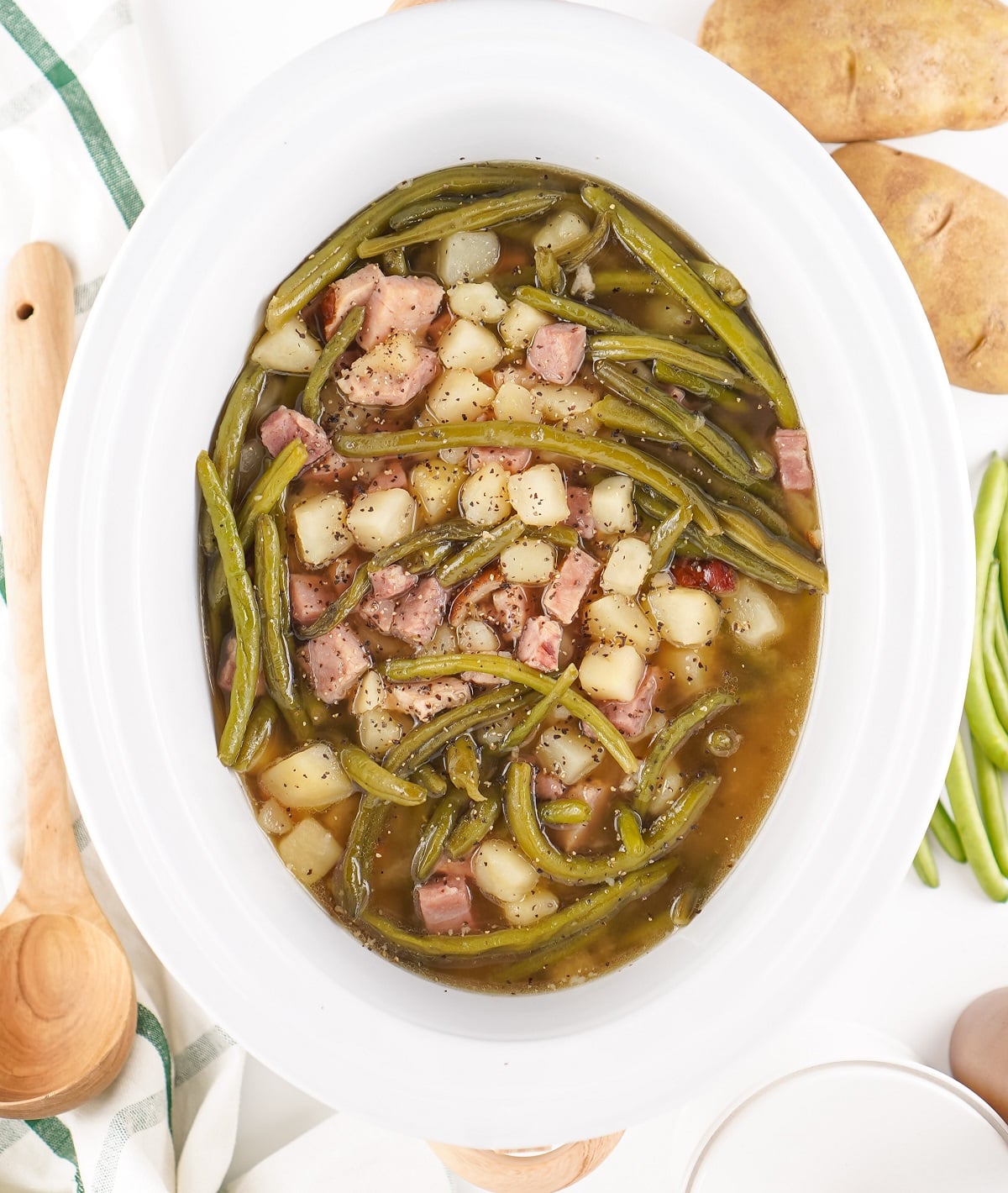 Top down view of slow cooker green beans with ham and potatoes.