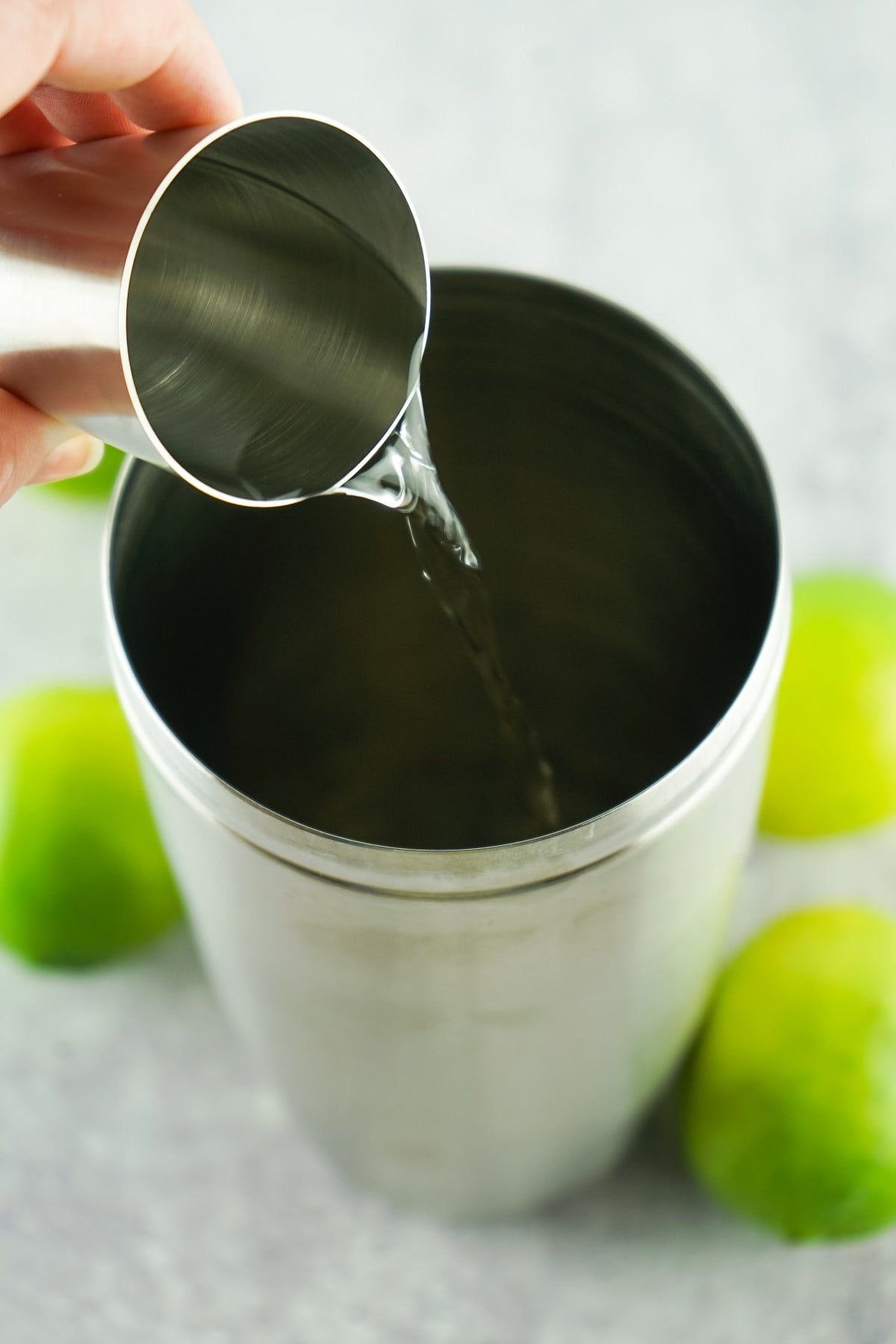 Vodka is poured into a cocktail shaker. 
