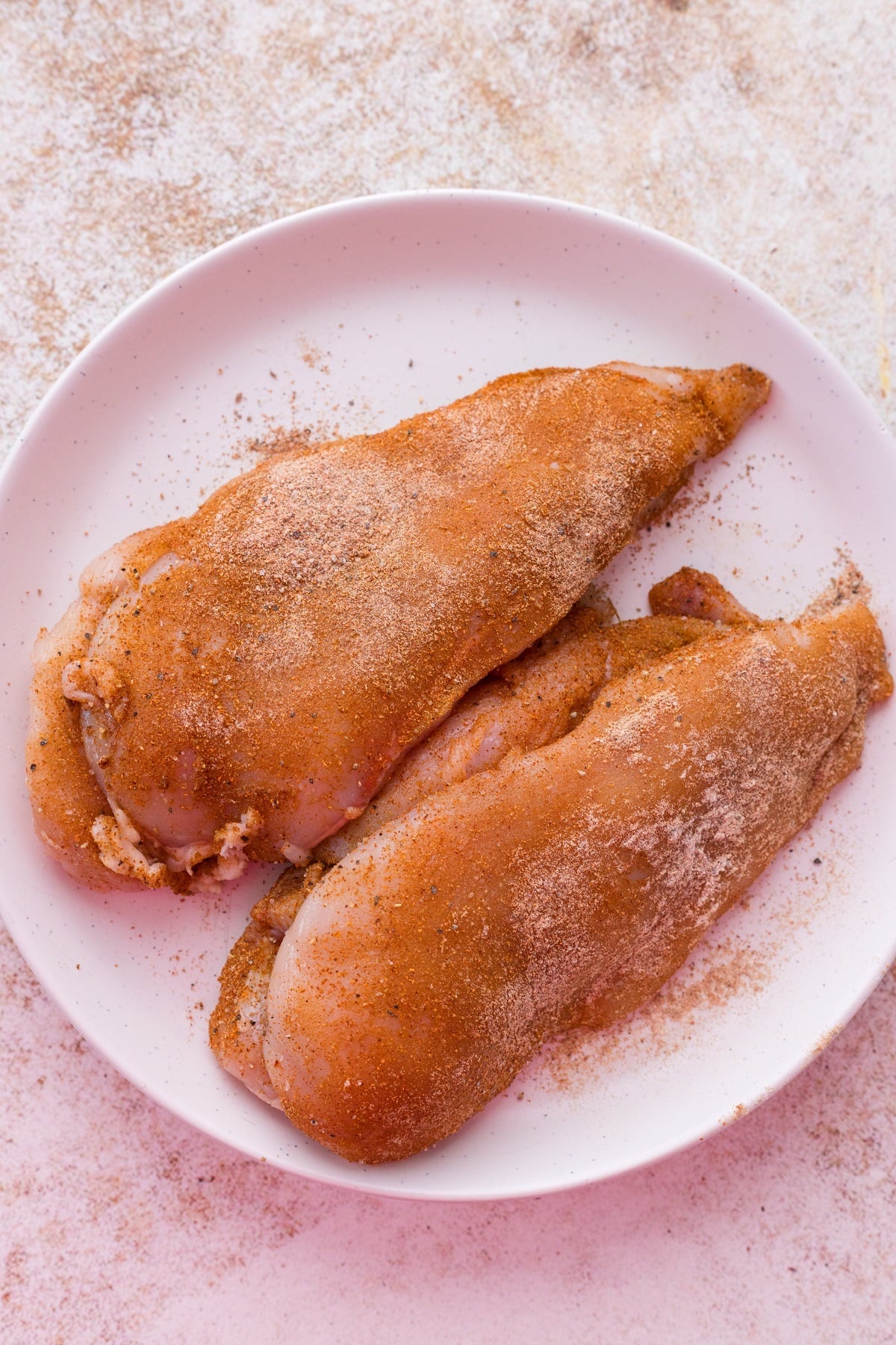 Chicken breasts are coated with oil and seasoned.