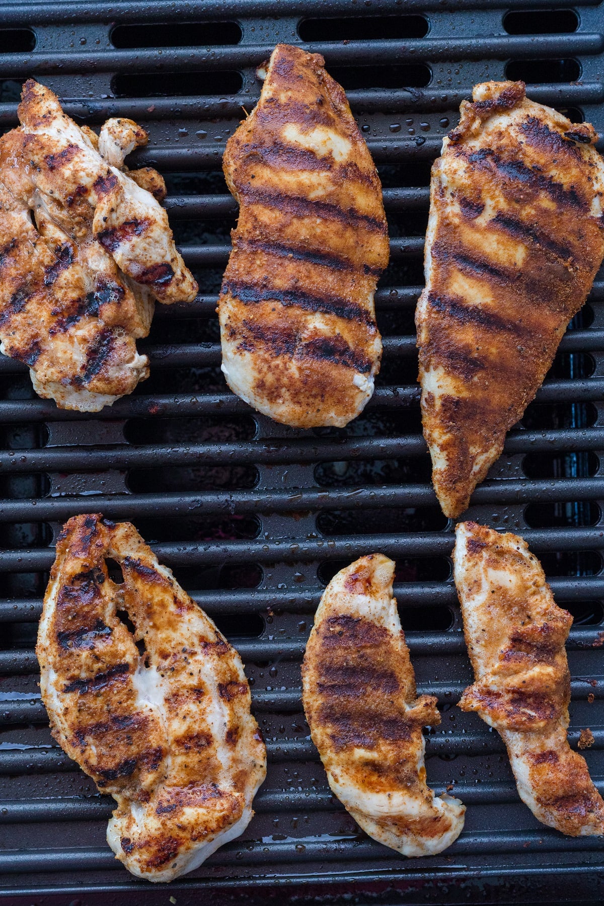 Seasoned chicken breast is cooked on a grill.