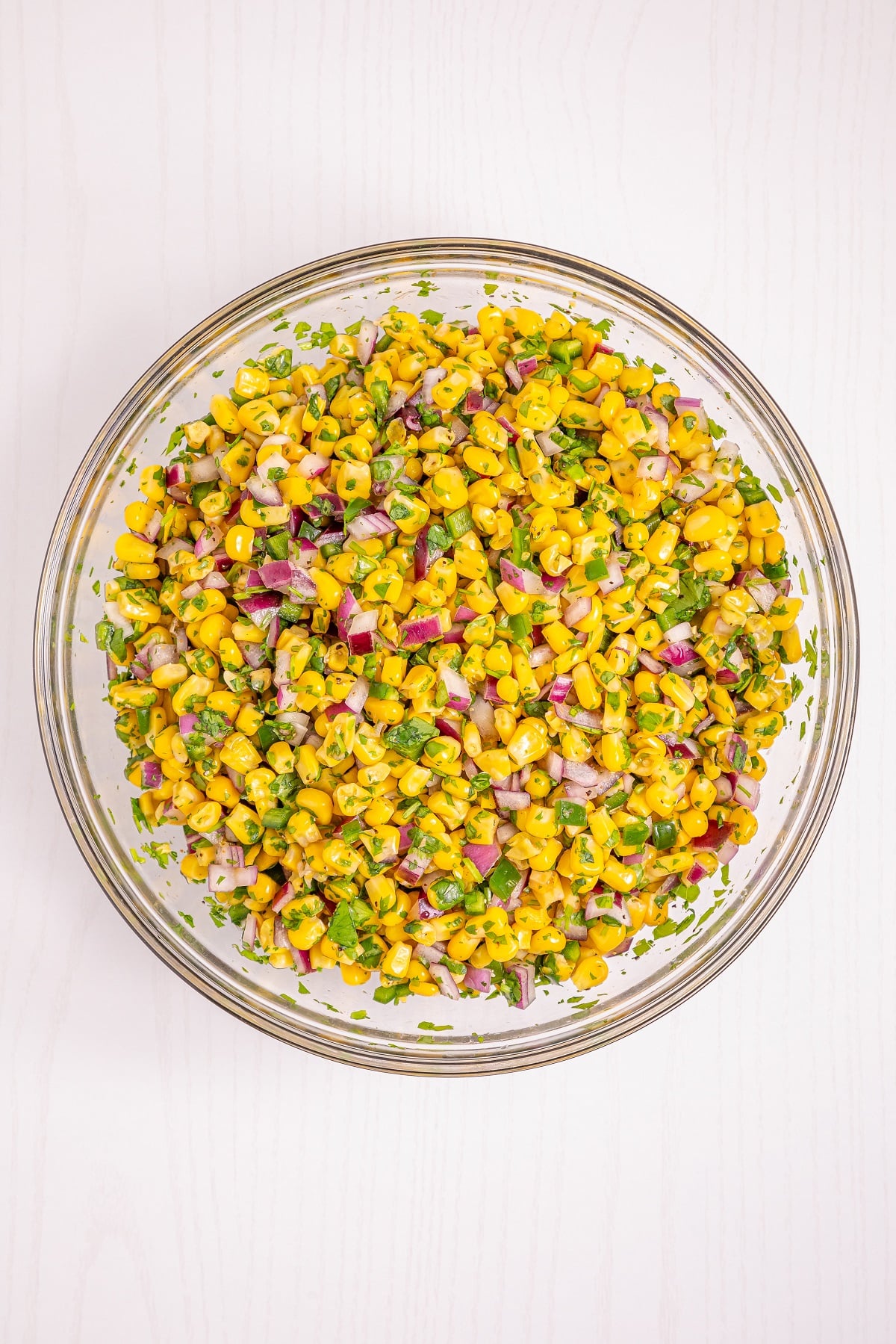 Corn salsa ingredients are mixed in a  bowl. 