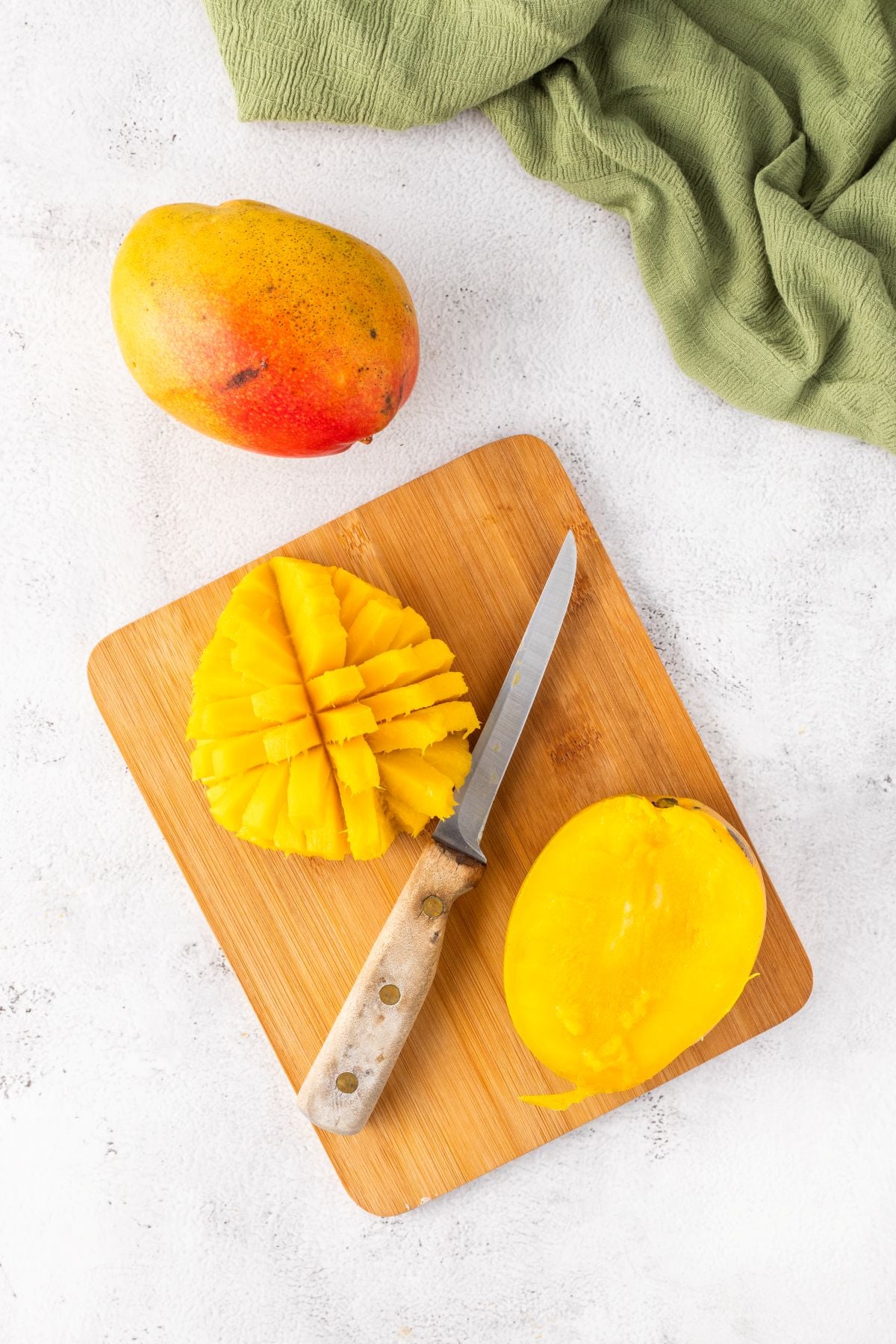 A mango is sliced on a cutting board. 