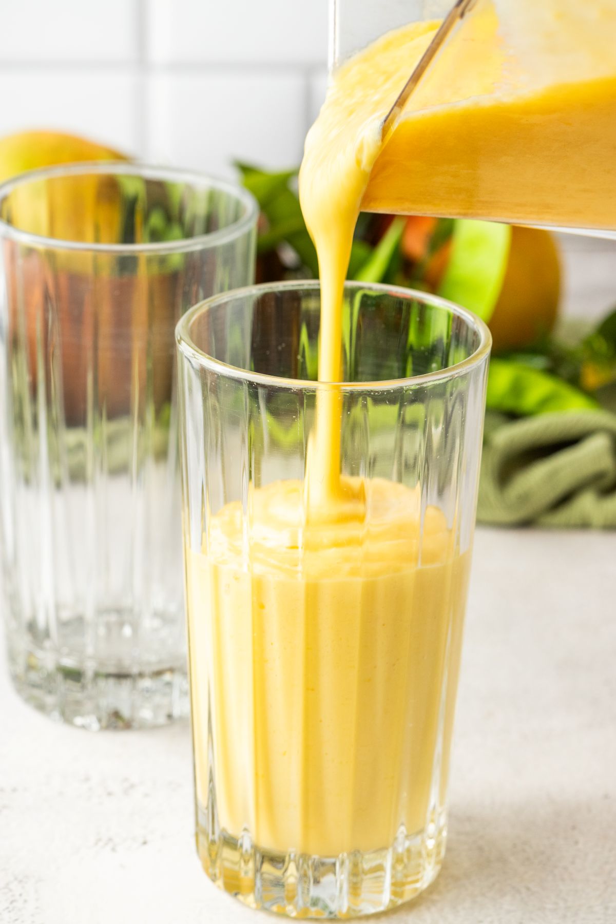 Mango milk shake is poured from the blender into two glasses. 
