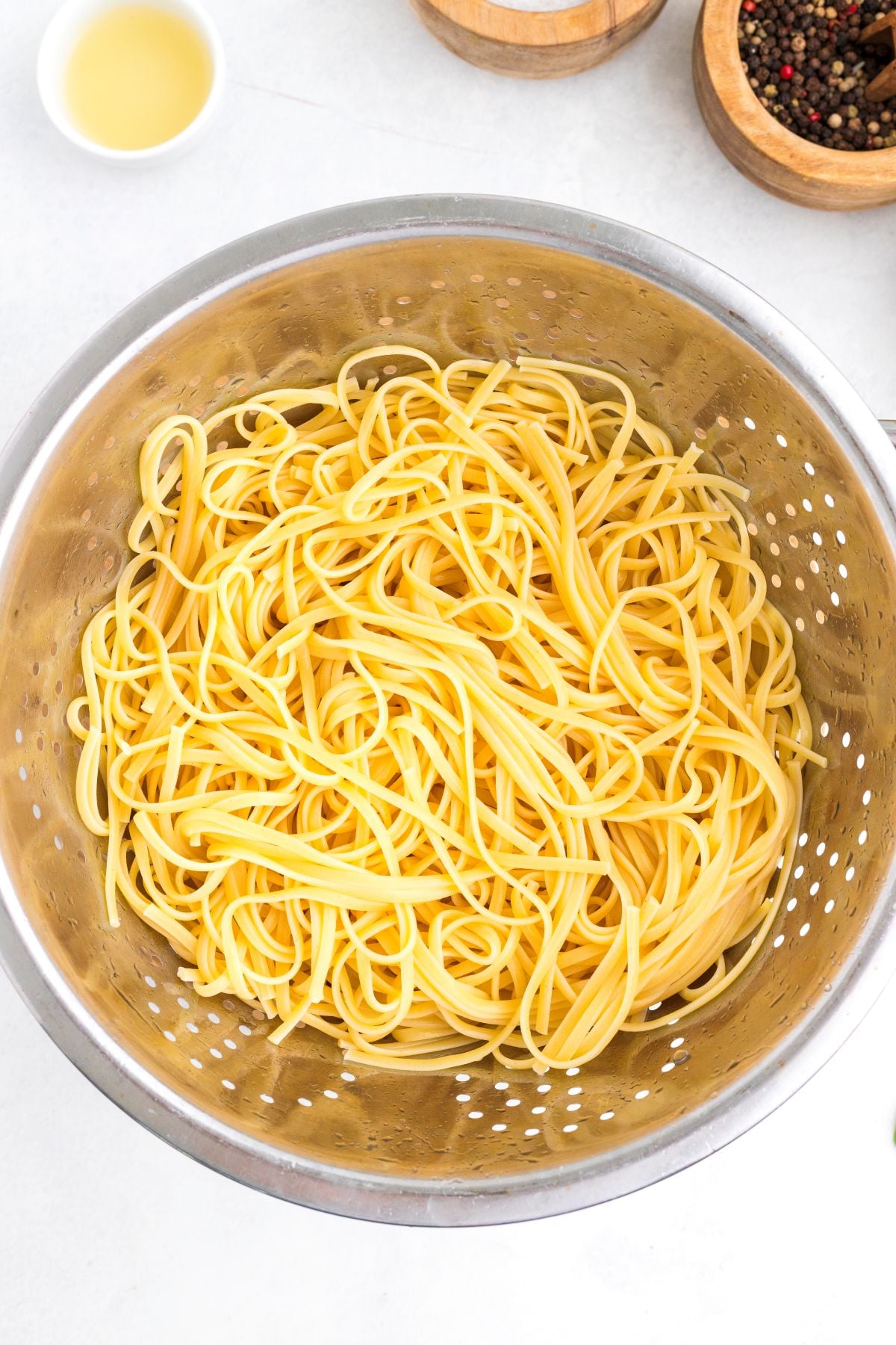 Cooked linguini drains in a colander. 