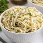 A white bowl filled with creamy garlic and herb Boursin pasta, garnished with fresh chopped basil