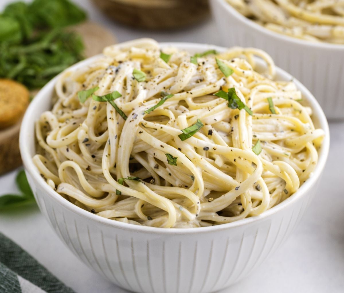 A bowl of creamy pasta topped with basil. 