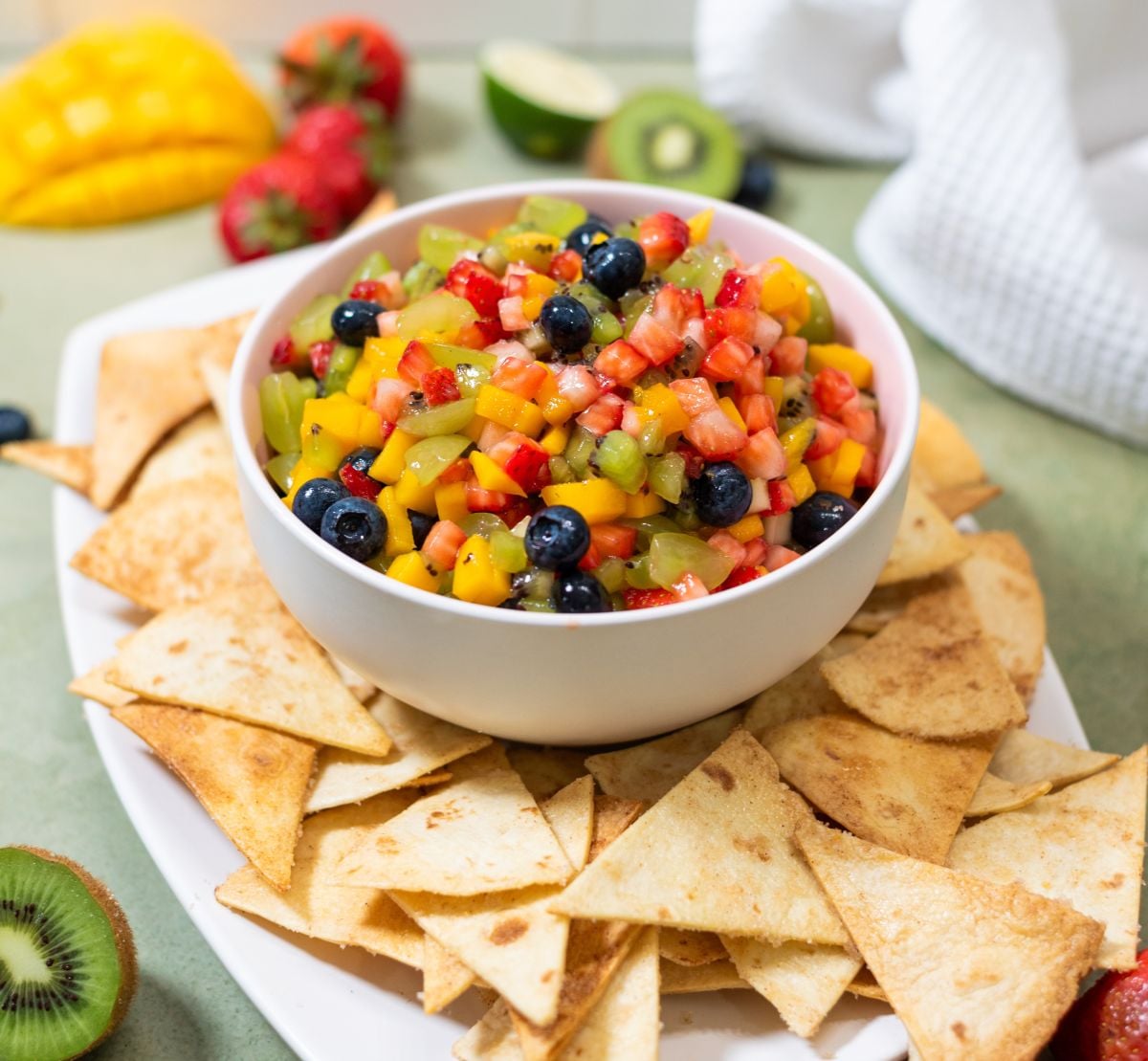 A platter of sweet pita chips and a bowl of fruit salsa.