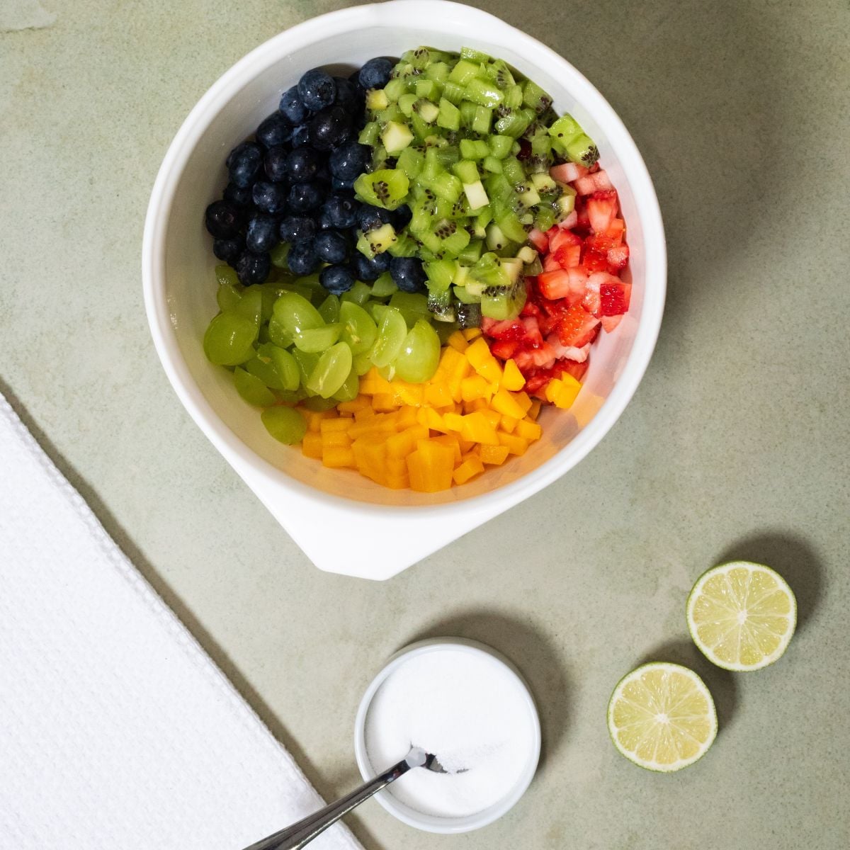 Chopped fruit is added to a bowl.