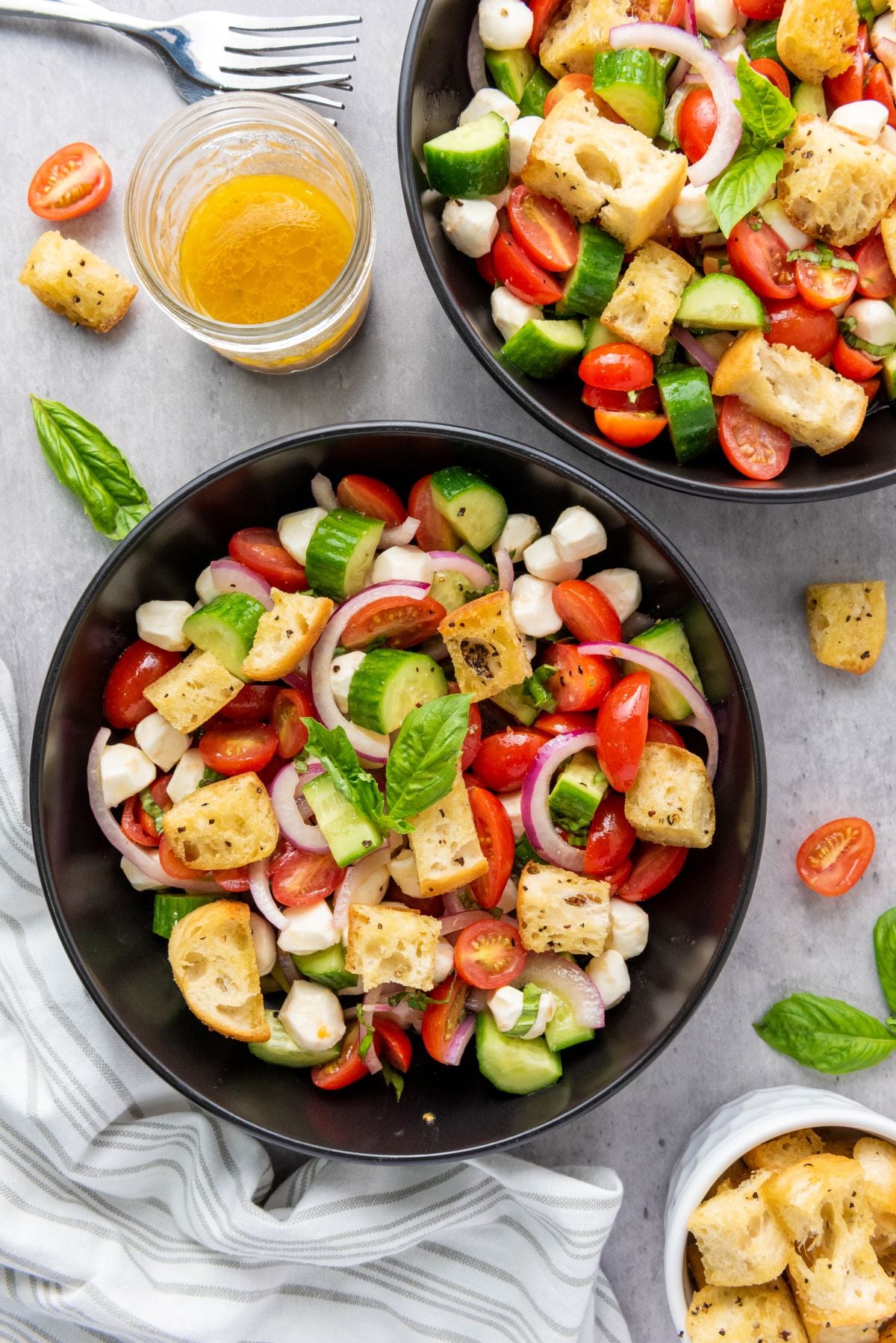 Panzanella salad is combined with dressing and served in bowls.