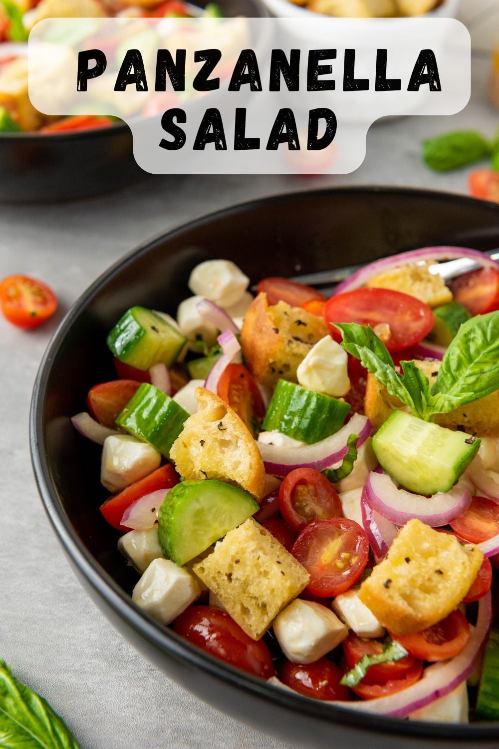 Tossed salad with cibatta bread cubes in a black bowl.