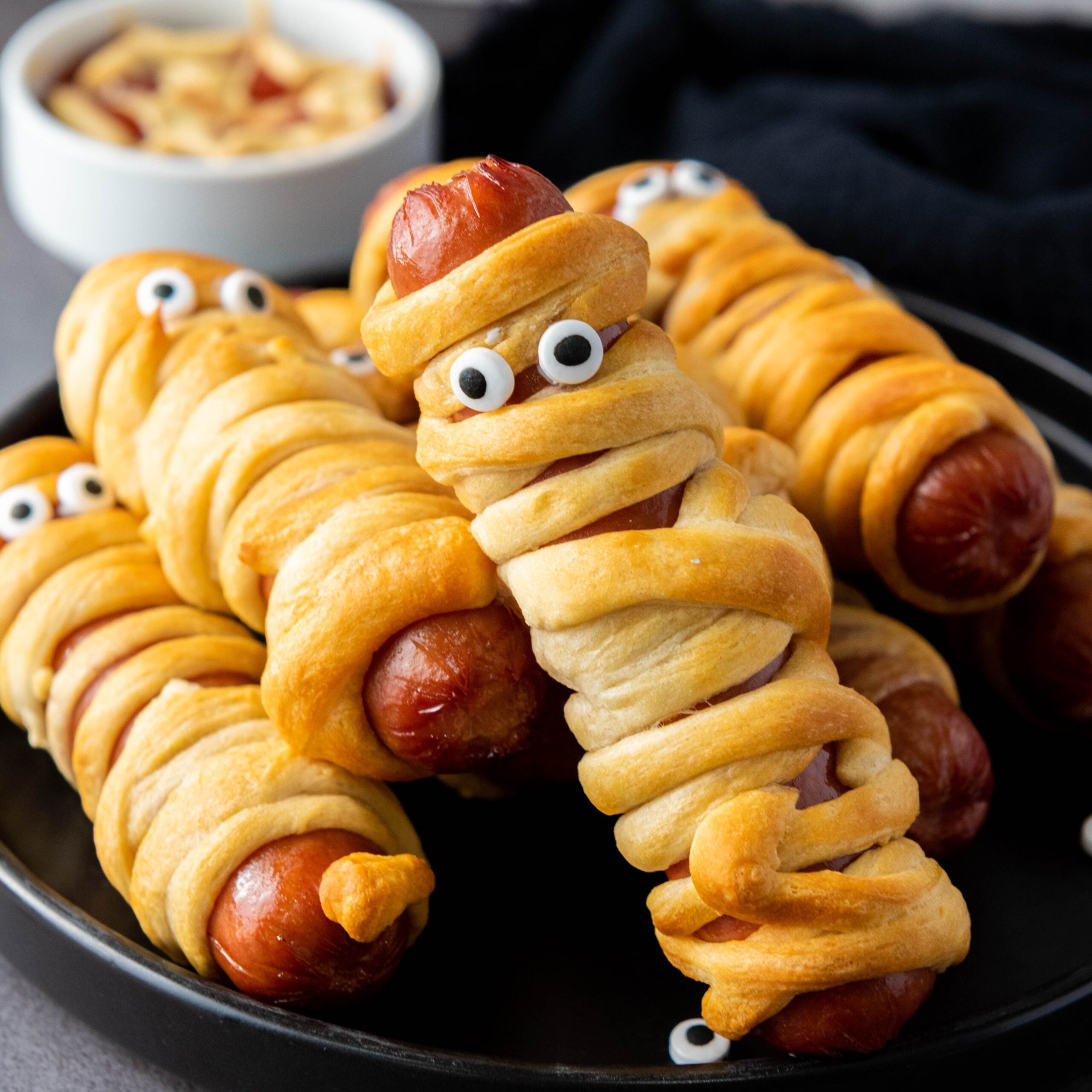 Crescent roll wrapped mummy hot dogs on a platter.