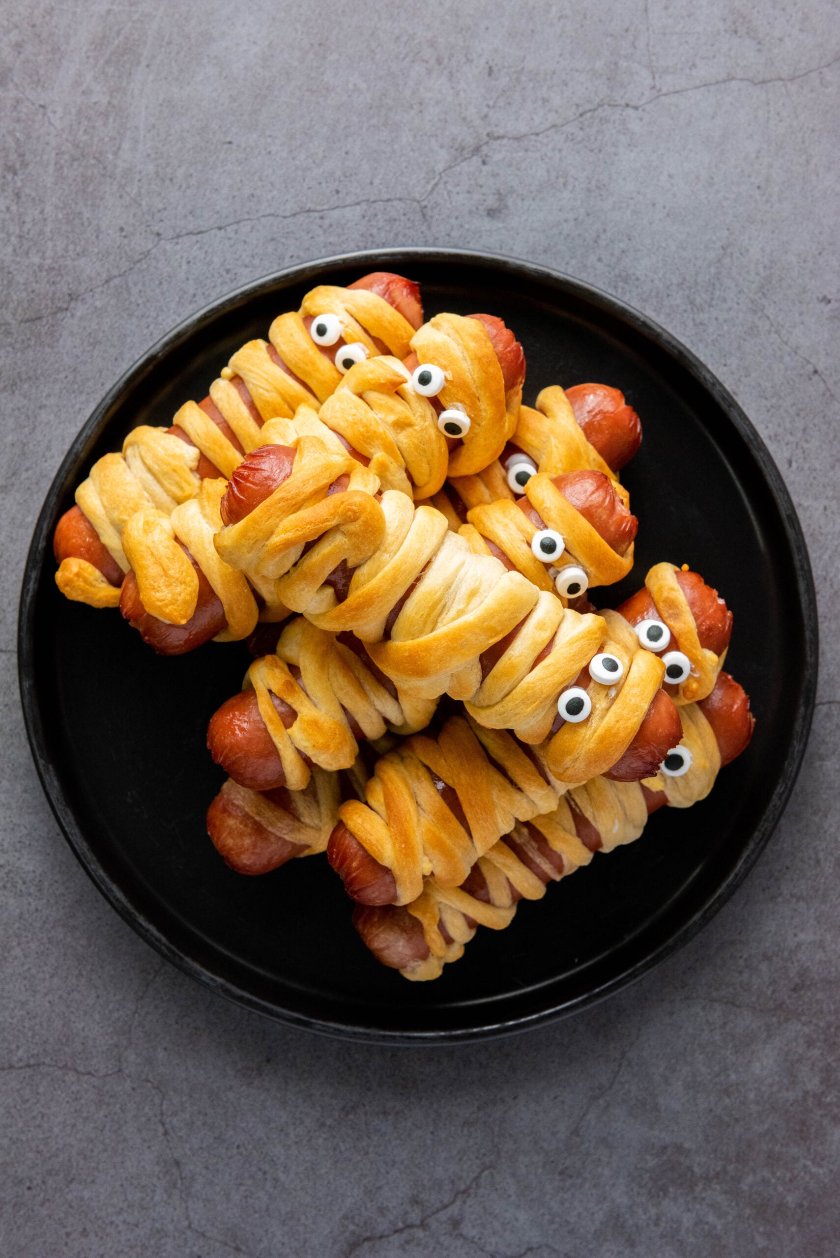 Candy eyes are added to mummy hot dogs.